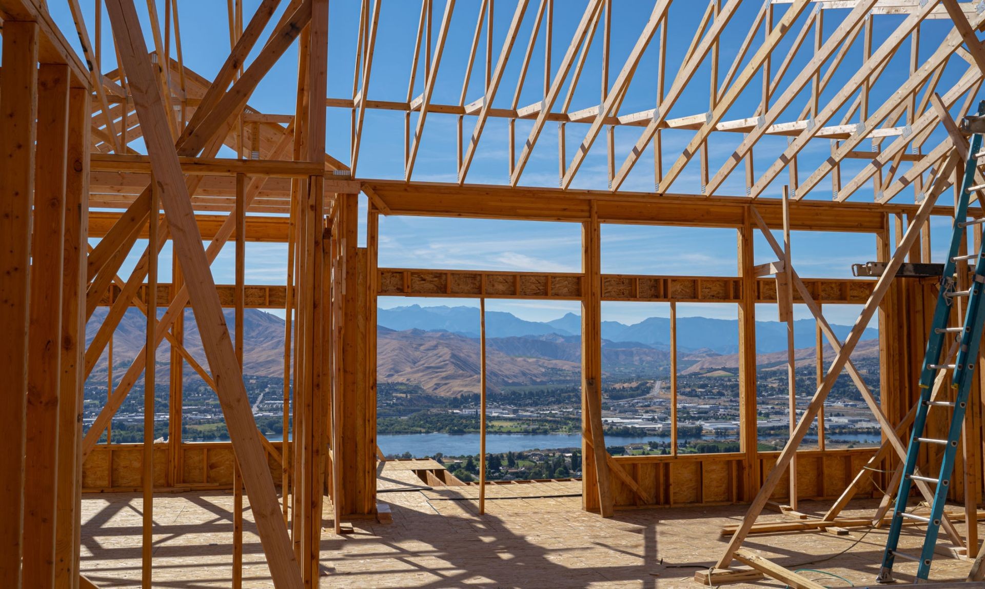 Framed structure of a house under construction with scenic mountain view in the background.