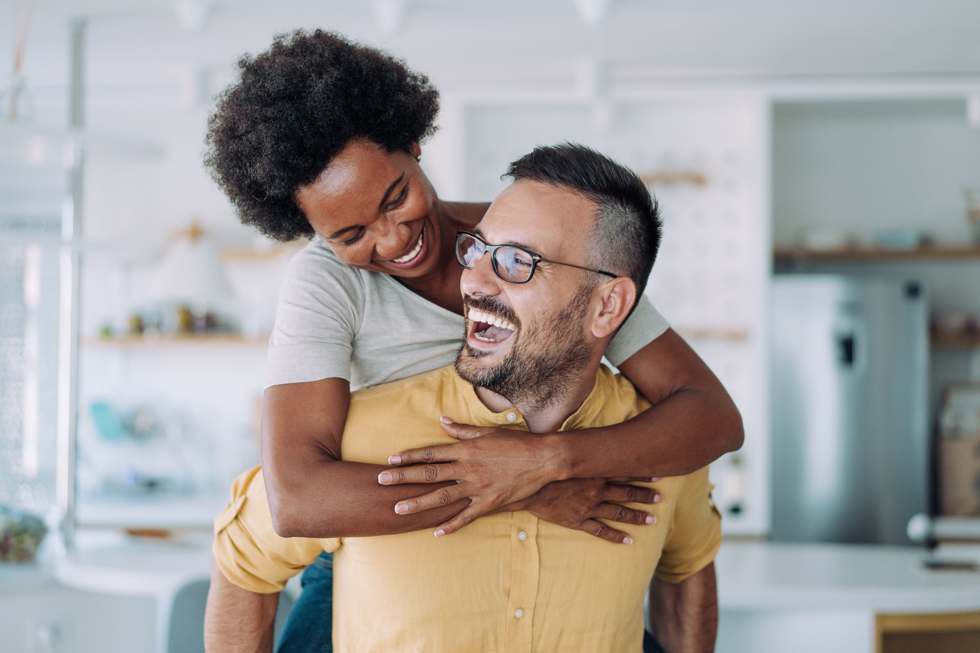 Young happy couple piggybacking at home.