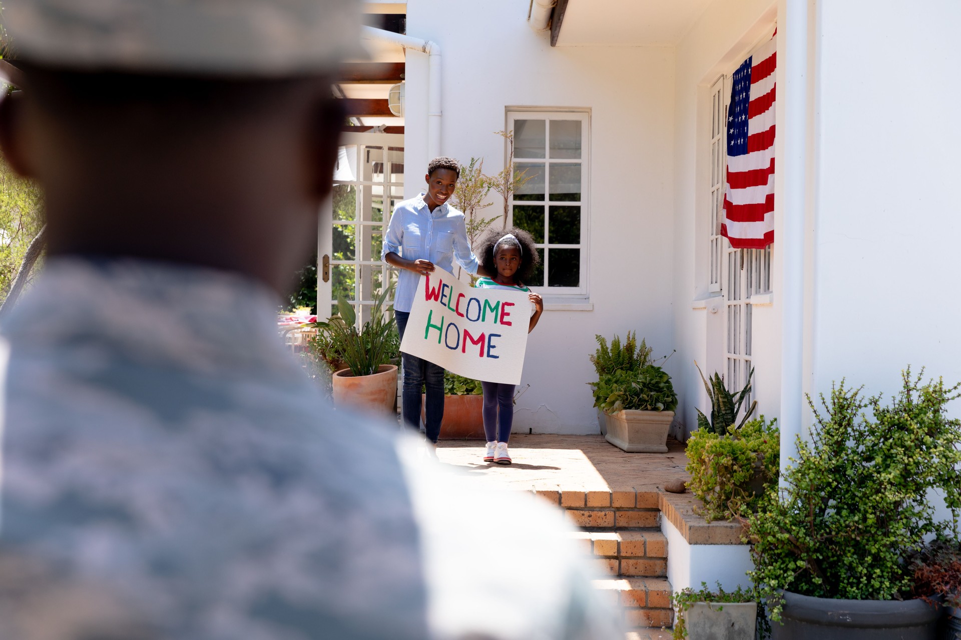 African American woman and her daughter standing  welcoming an African American soldier