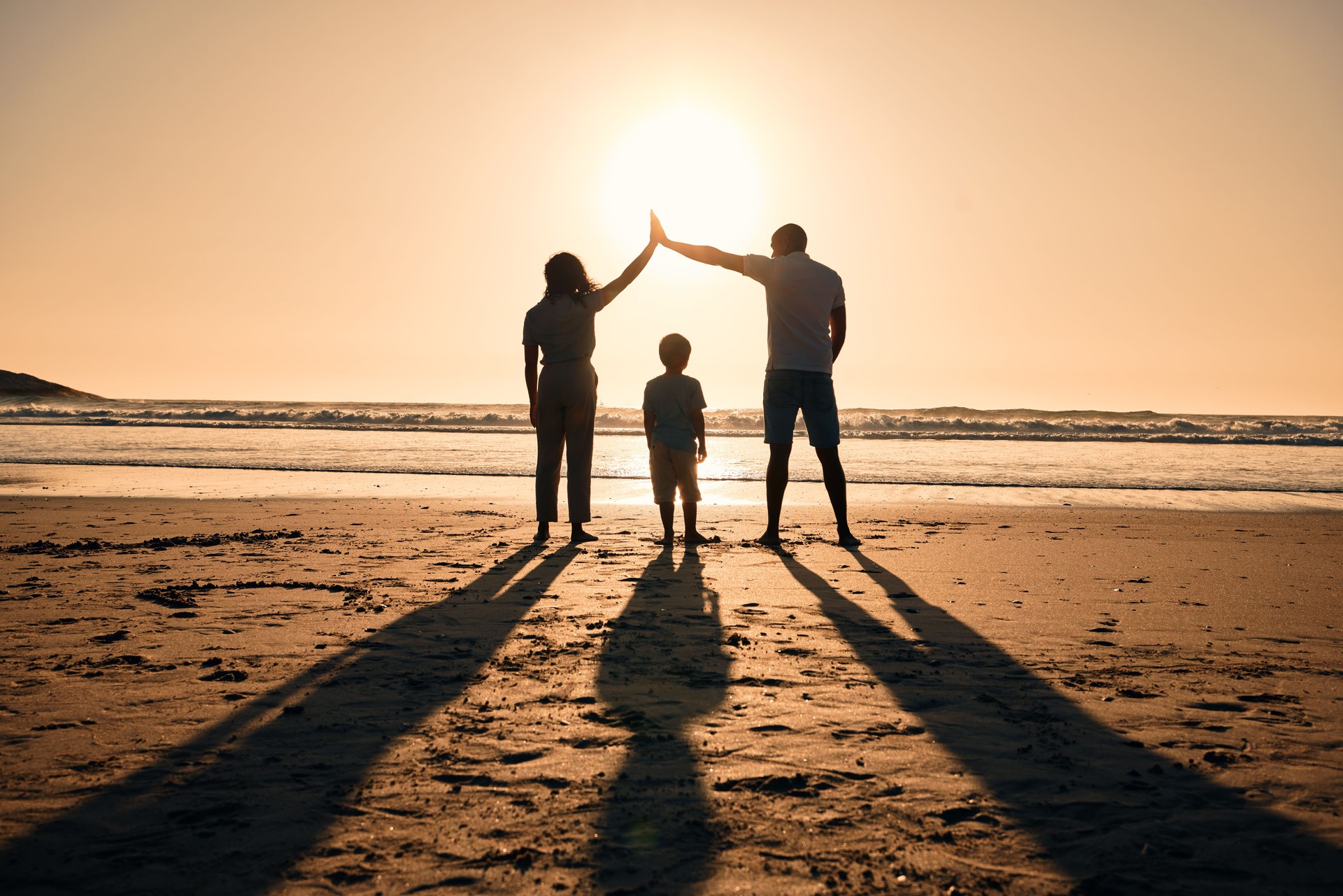 Family silhouette at beach, protection and sunset with people, safety and security with parents and child outdoor. Mother, father and kid in nature, back and ocean view with love, care and support