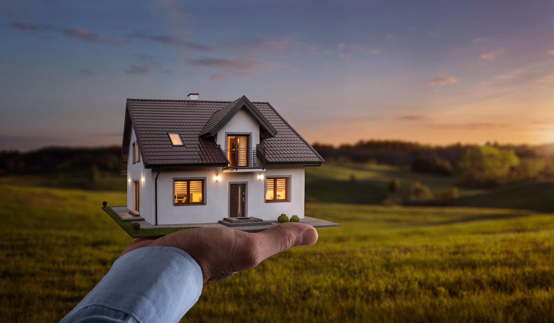 Male hand showing, offering a new dream house at the empty field with copy space