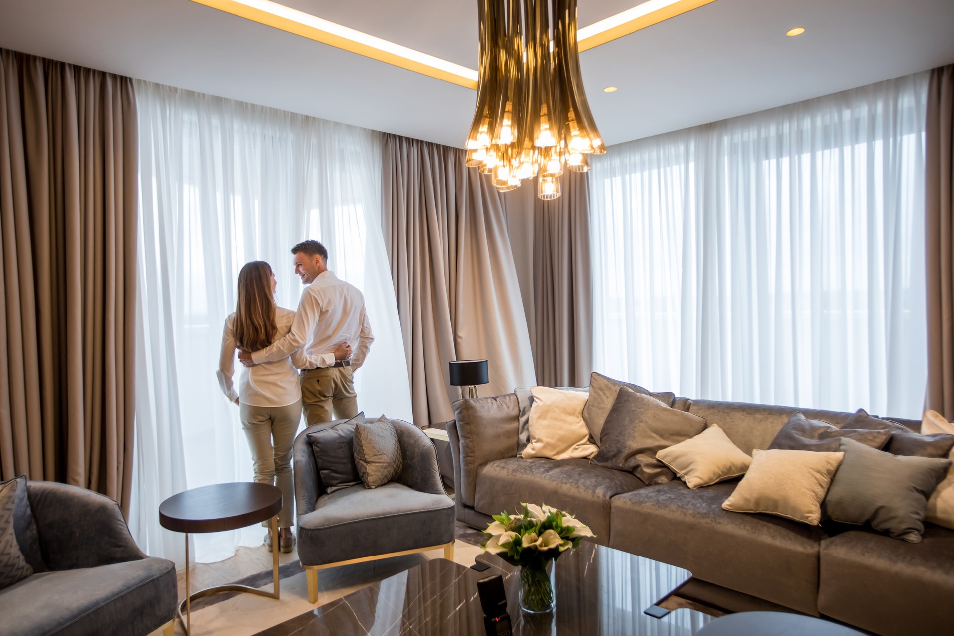 Couple embracing standing in living room of a contemporary apartment