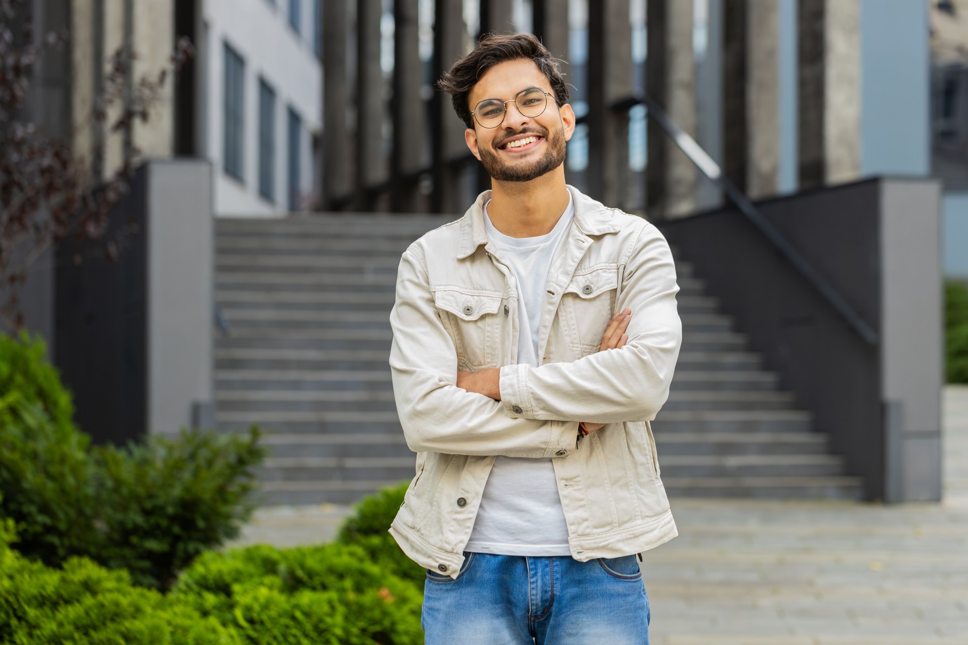 Happy Indian man smiling looking away dreaming, resting, good news, feel satisfied in city street