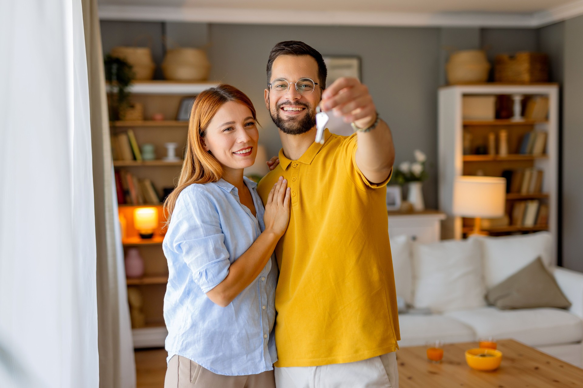 Smiling couple in cozy living room holding a key